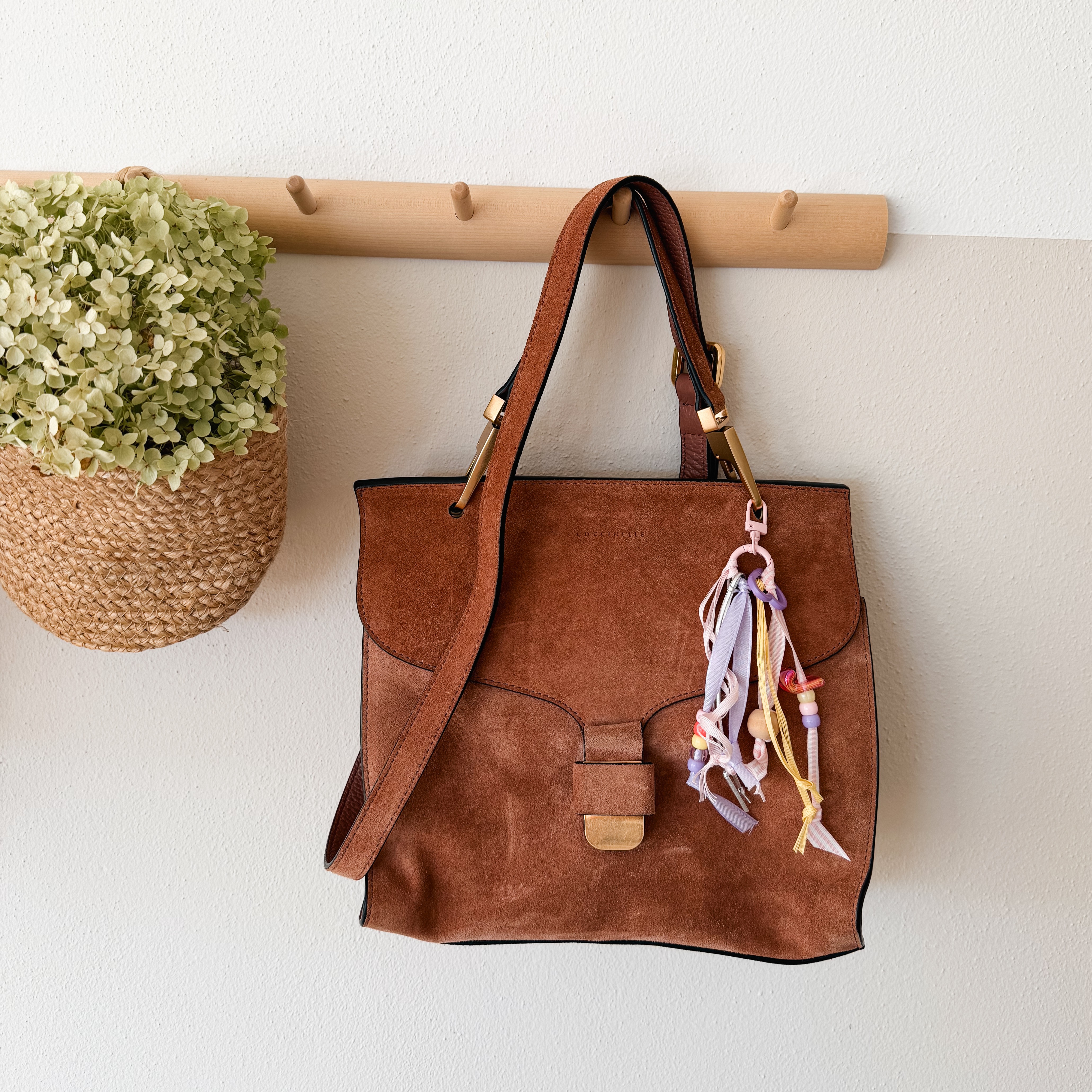 Selbst gestalteter Anhänger aus rosa und gelben Bändern an einer braunen Tasche